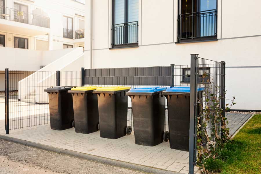 Gardien d'immeuble rentrant les conteneurs sous un soleil de plomb en pleine canicule